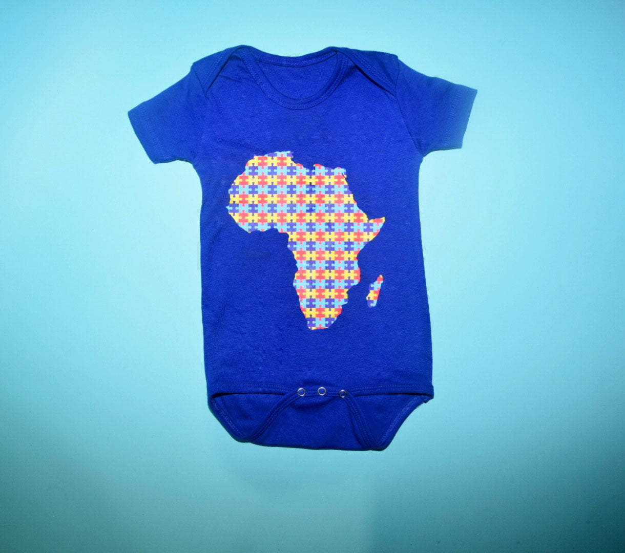 Map of Africa onesie with multi colored puzzle pieces taking shape of the motherland.